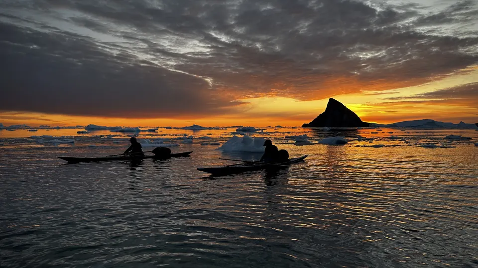 Qajaqs moving through open water near ice and headland in Qimusseriarsuaq.